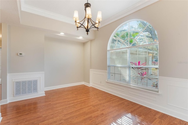 unfurnished dining area featuring an inviting chandelier, hardwood / wood-style floors, and ornamental molding