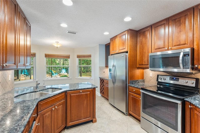 kitchen featuring stainless steel appliances, sink, and dark stone countertops