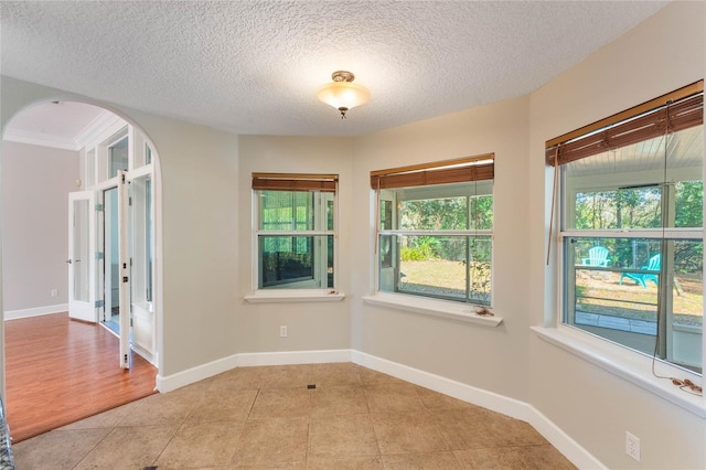 unfurnished room featuring a textured ceiling and light tile patterned floors