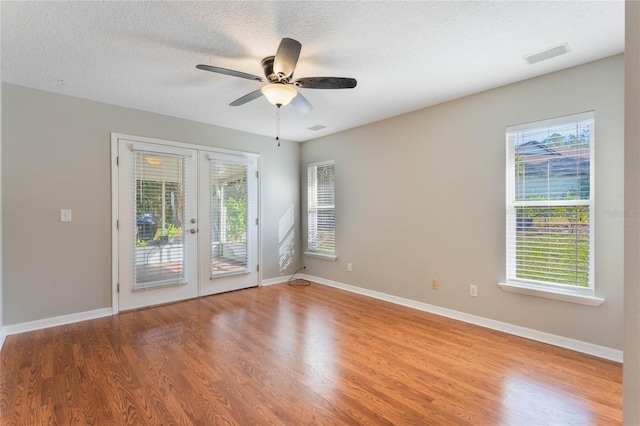 unfurnished room with french doors, ceiling fan, a textured ceiling, and light wood-type flooring