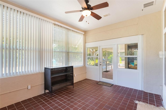 unfurnished sunroom with ceiling fan