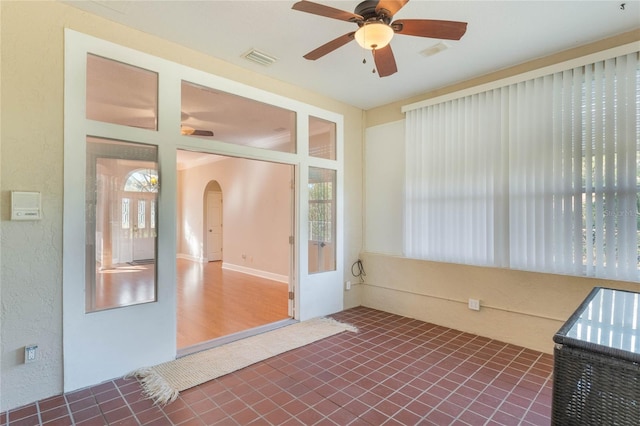 unfurnished sunroom with ceiling fan