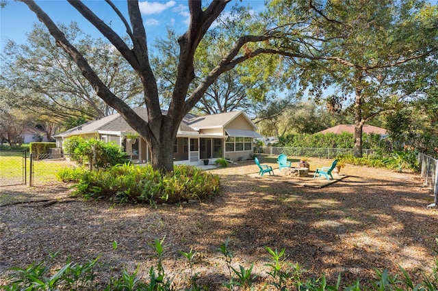 view of yard featuring a sunroom and a fire pit