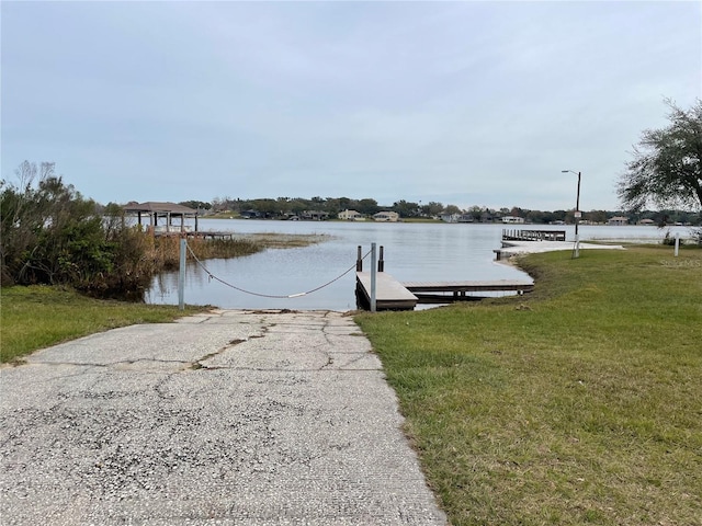 view of dock with a water view and a yard