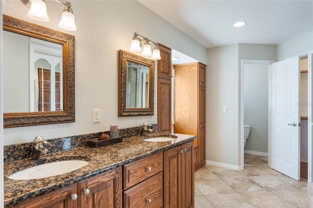 bathroom with vanity, a textured ceiling, and toilet