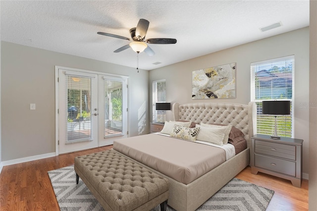 bedroom with multiple windows, access to outside, french doors, and light wood-type flooring