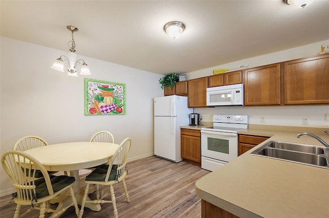 kitchen with sink, white appliances, hanging light fixtures, a chandelier, and light wood-type flooring