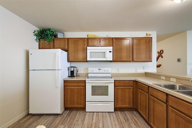 kitchen with white appliances, light hardwood / wood-style flooring, and a textured ceiling