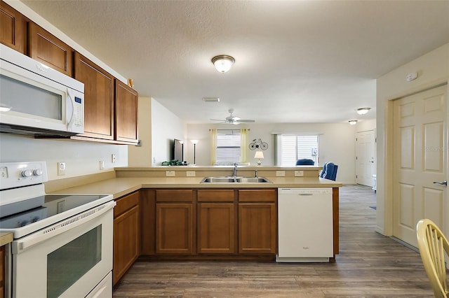 kitchen with dark hardwood / wood-style floors, sink, white appliances, kitchen peninsula, and a textured ceiling