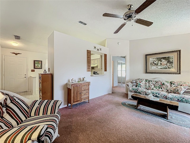 carpeted living room featuring ceiling fan and a textured ceiling