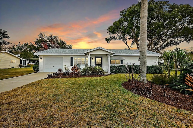 ranch-style home featuring a garage and a lawn