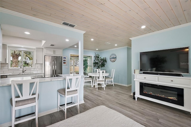 kitchen featuring sink, stainless steel fridge, backsplash, white cabinets, and a kitchen bar