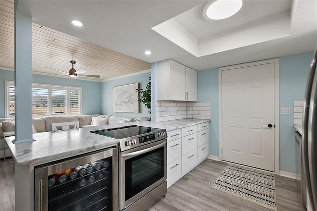 kitchen with stainless steel electric range, white cabinetry, tasteful backsplash, kitchen peninsula, and beverage cooler