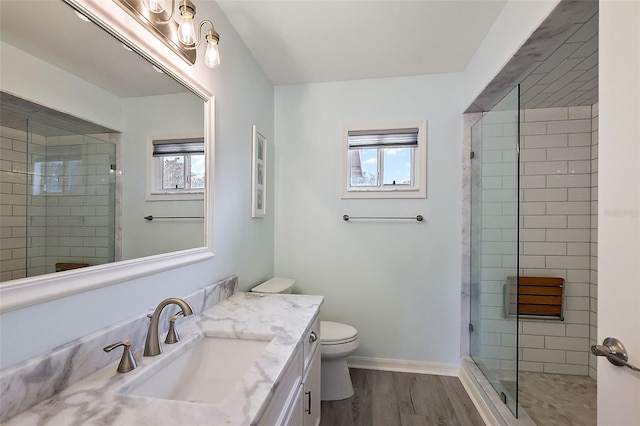 bathroom featuring vanity, toilet, a shower with shower door, and wood-type flooring