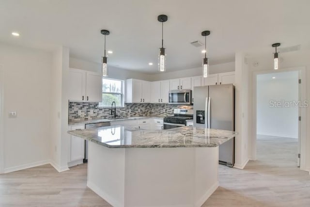 kitchen with appliances with stainless steel finishes, sink, white cabinets, decorative backsplash, and a center island