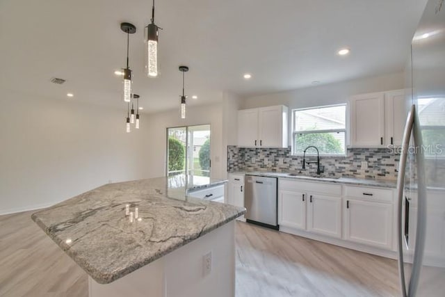 kitchen featuring sink, white cabinetry, hanging light fixtures, appliances with stainless steel finishes, and a kitchen island