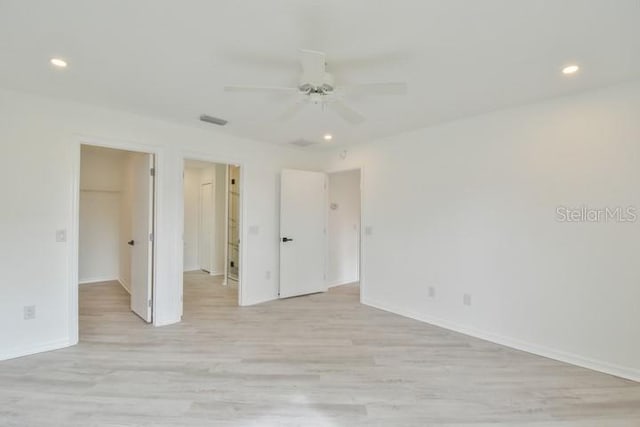 unfurnished bedroom with ceiling fan, a spacious closet, light hardwood / wood-style floors, and a closet