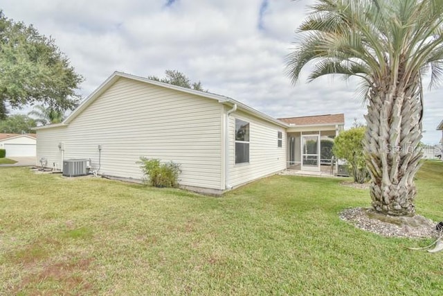 view of property exterior featuring a sunroom, central AC unit, and a lawn