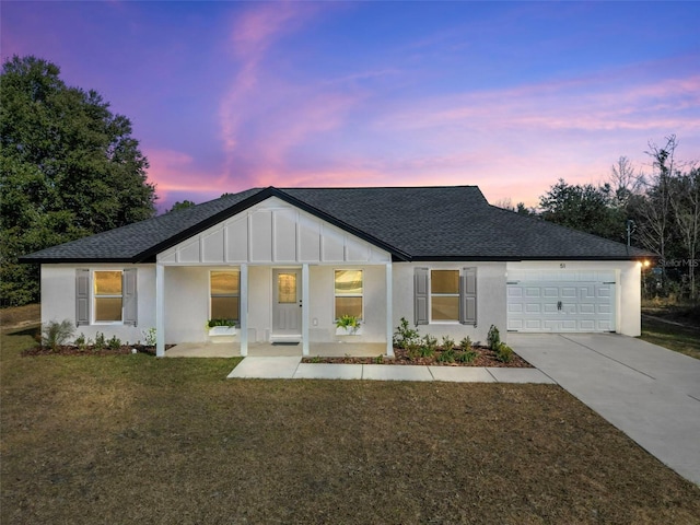 view of front of house featuring a garage, covered porch, and a lawn