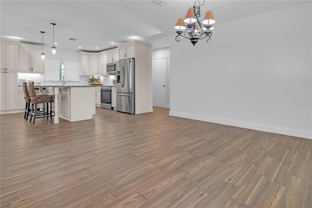 kitchen with stainless steel appliances, a kitchen island, a breakfast bar, and pendant lighting