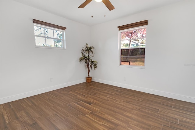 spare room with dark wood-type flooring, ceiling fan, and a healthy amount of sunlight