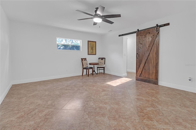 unfurnished room featuring a barn door and ceiling fan