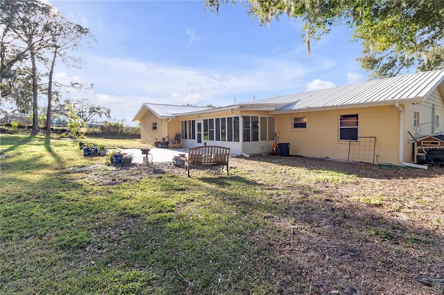 rear view of house featuring a yard, a patio, and a sunroom