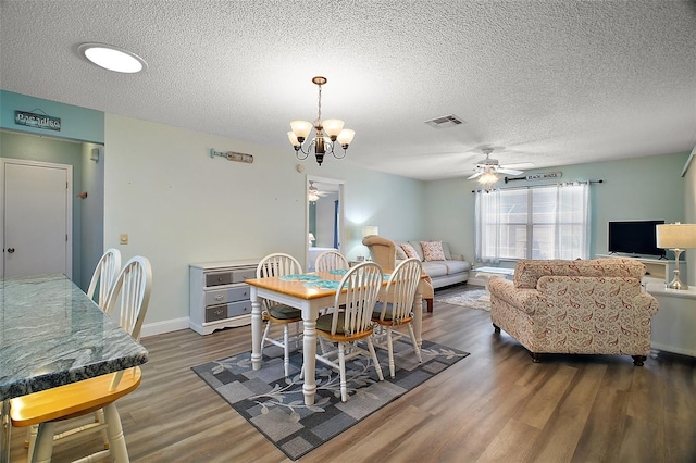 dining room featuring dark wood-type flooring, ceiling fan with notable chandelier, and a textured ceiling