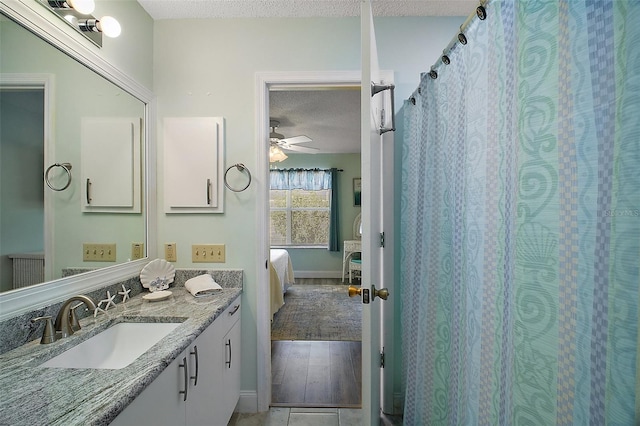 bathroom with ceiling fan, vanity, and a textured ceiling