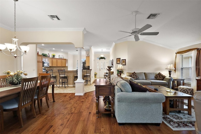 living room featuring ceiling fan with notable chandelier, dark wood-type flooring, visible vents, ornamental molding, and ornate columns