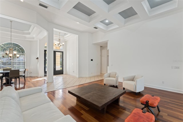 living room with coffered ceiling, a towering ceiling, and a notable chandelier