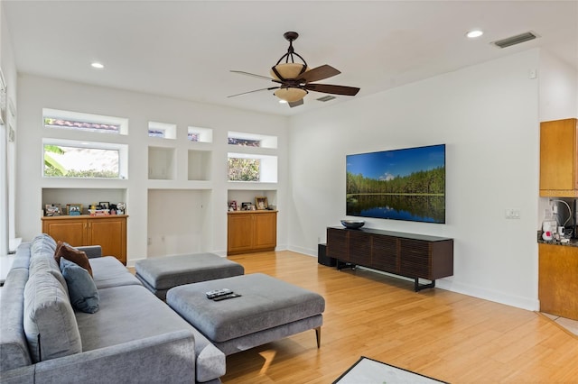 living room featuring ceiling fan, a wealth of natural light, built in features, and light wood-type flooring