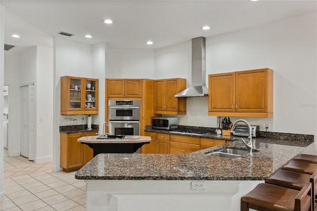 kitchen with a kitchen bar, kitchen peninsula, wall chimney exhaust hood, and appliances with stainless steel finishes