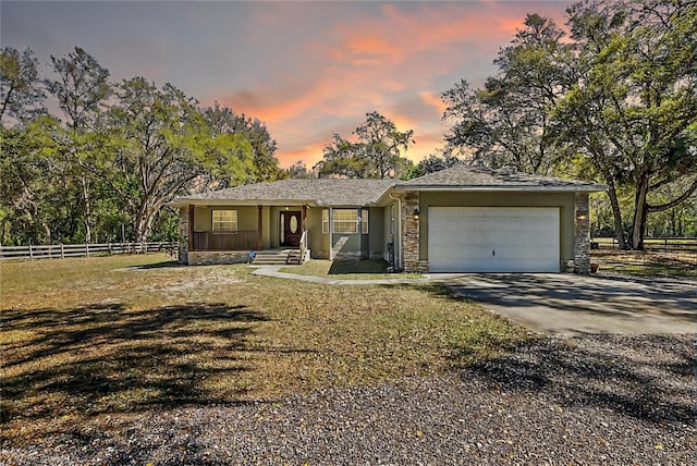 ranch-style home featuring fence, driveway, an attached garage, stucco siding, and stone siding