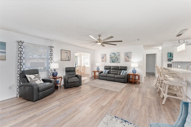 living room featuring ceiling fan, a textured ceiling, and light hardwood / wood-style floors