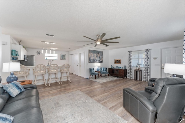 living room with a healthy amount of sunlight, ceiling fan, a textured ceiling, and light wood-type flooring