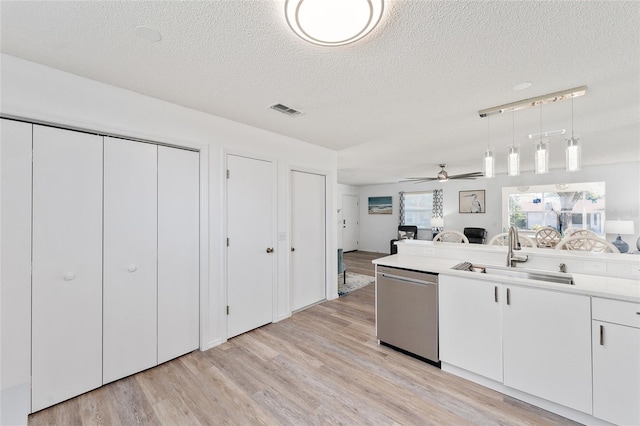 kitchen with sink, dishwasher, white cabinetry, hanging light fixtures, and a textured ceiling