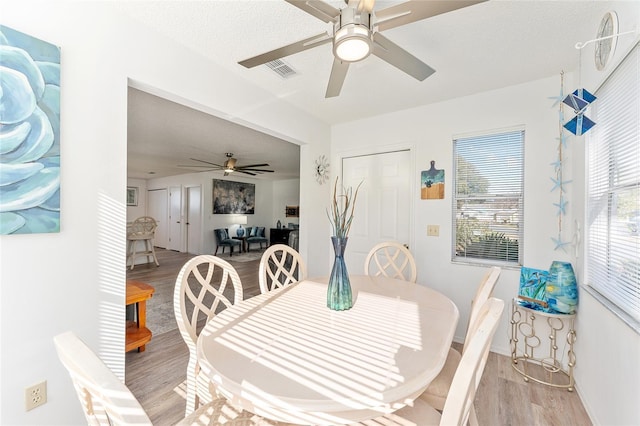 dining area featuring ceiling fan, a textured ceiling, and light wood-type flooring