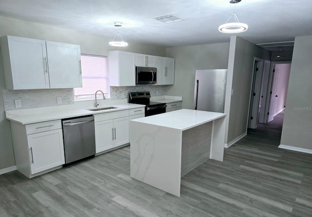 kitchen featuring stainless steel appliances, hanging light fixtures, sink, and white cabinets