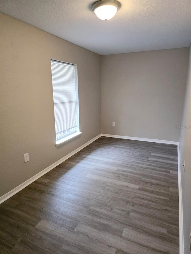 unfurnished room with a textured ceiling and dark hardwood / wood-style flooring