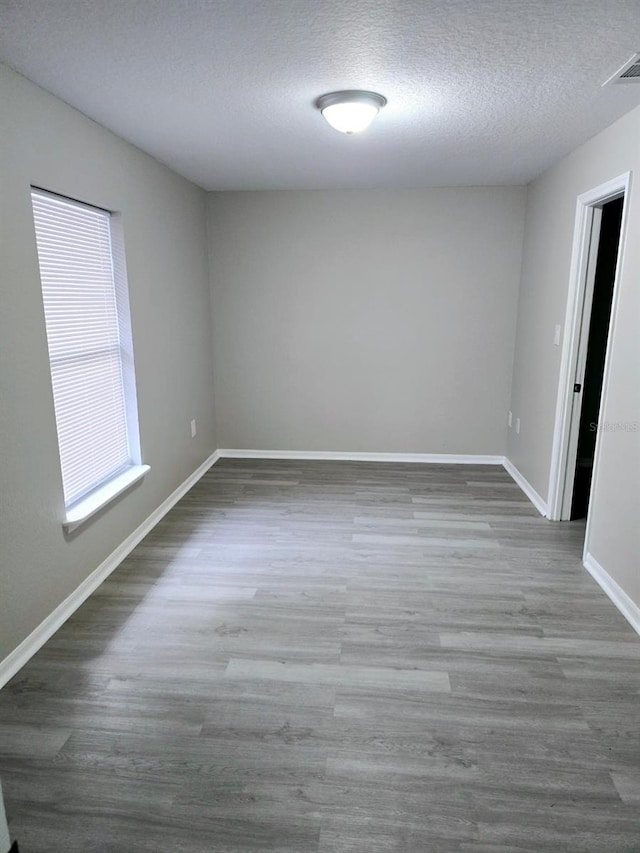 empty room featuring wood-type flooring and a textured ceiling