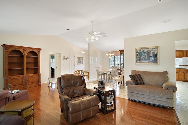 living room with lofted ceiling, ceiling fan with notable chandelier, and light hardwood / wood-style flooring