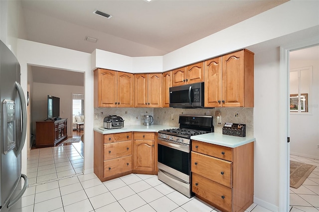 kitchen with light tile patterned flooring, stainless steel appliances, and backsplash