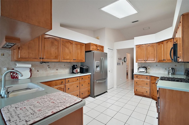 kitchen featuring sink, decorative backsplash, light tile patterned floors, stainless steel fridge with ice dispenser, and gas range oven