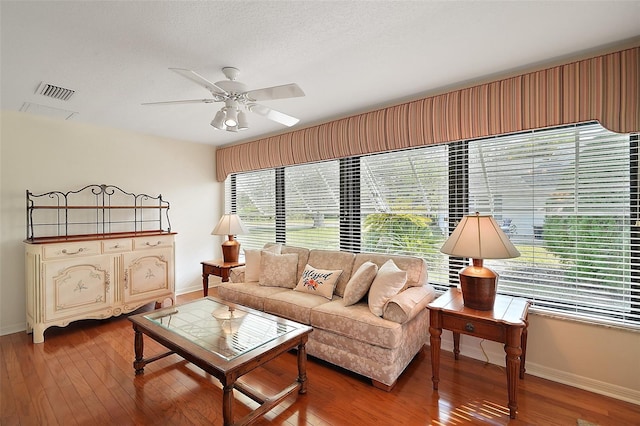 living room featuring ceiling fan, hardwood / wood-style floors, and a textured ceiling