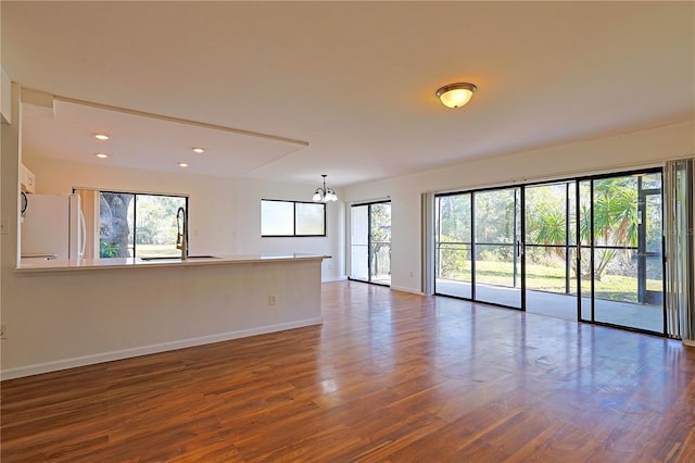 unfurnished room with an inviting chandelier, wood finished floors, baseboards, and a sink