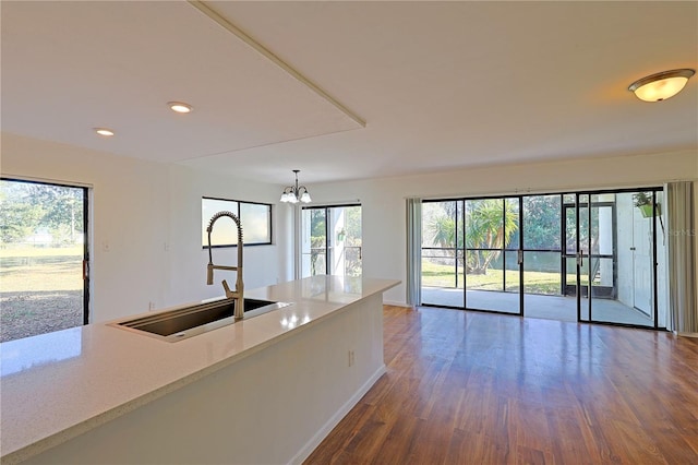 kitchen featuring baseboards, open floor plan, recessed lighting, wood finished floors, and a sink