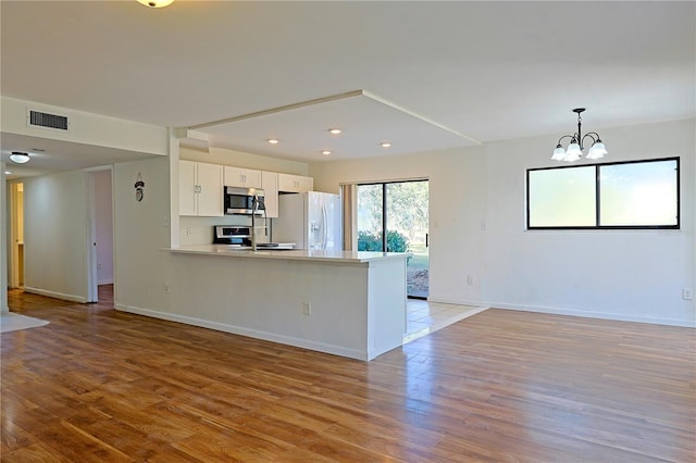 kitchen with stainless steel appliances, white cabinetry, light wood-type flooring, and kitchen peninsula