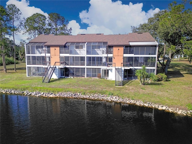 back of property with stairway, a yard, a water view, and a sunroom