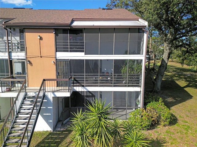 rear view of house featuring stairway, a sunroom, and roof with shingles